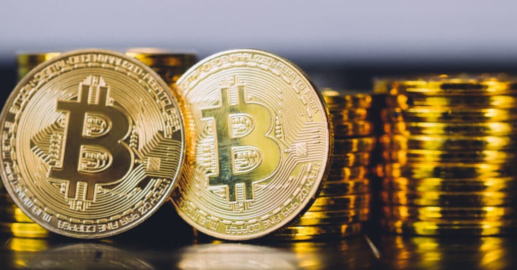 Header banner with two physical Bitcoin coins in sharp focus and blurred stacks of cryptocurrency coins behind