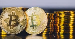 Header banner with two physical Bitcoin coins in sharp focus and blurred stacks of cryptocurrency coins behind